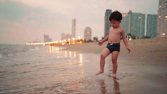 慢动作:亚洲男婴在沙滩上享受和玩耍