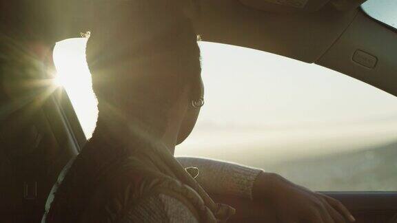 一段4k视频一个不知名的女人独自坐在车里享受公路旅行中的日落