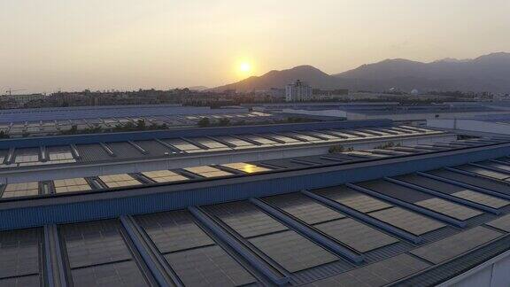 日落时分安装在大型工厂屋顶上的太阳能电池板的航拍照片