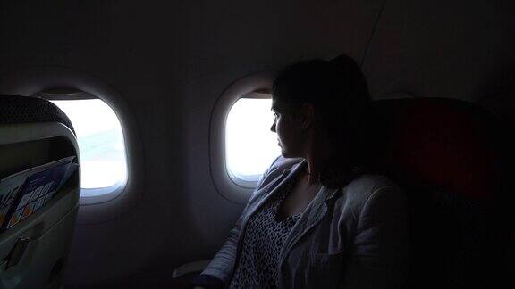 在飞机上透过窗户看的女人