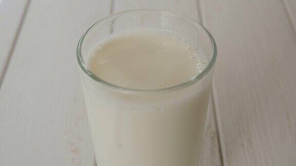 一滴牛奶落进满杯牛奶中在一个轻木制背景上