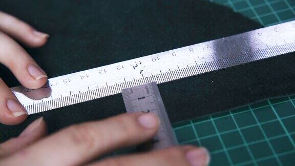 裁缝移动金属尺测量黑色皮革布