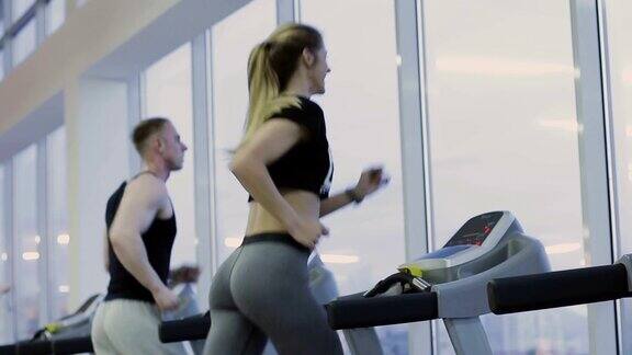 一个男人和一个女孩在健身俱乐部的跑步机上训练