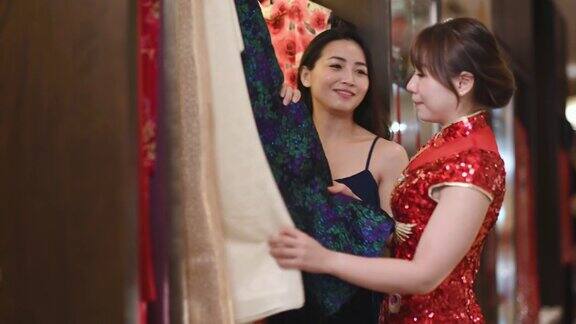 亚洲华人美女在中国传统精品店的衣架上挑选旗袍