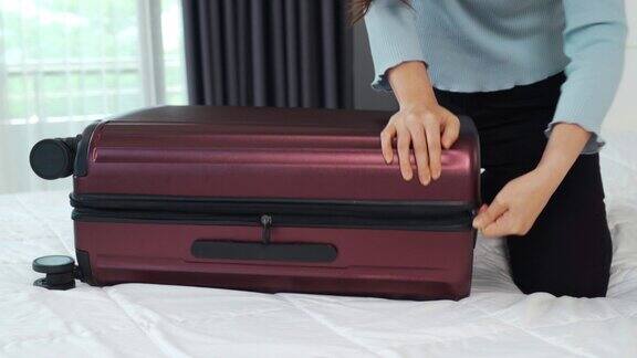 在家里的床上手持拉链将行李箱拉上构思假日旅行