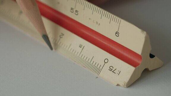 特写男性的手使用三角形比例尺与木制铅笔在白纸上绘图工具