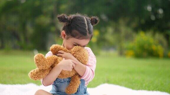 小女孩在花园里玩玩具熊