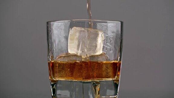 将朗姆酒倒入冰杯中在孤立的灰色背景上