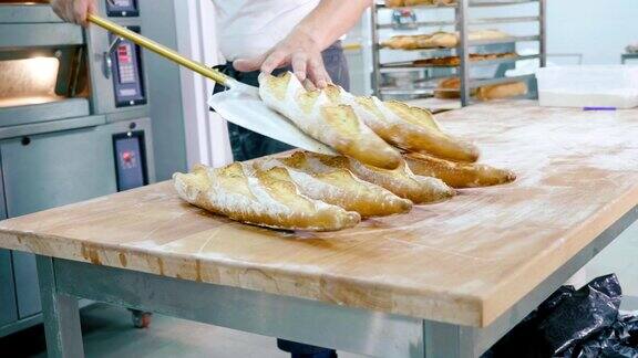 在商业厨房里专业面包师从烤箱中取出面包