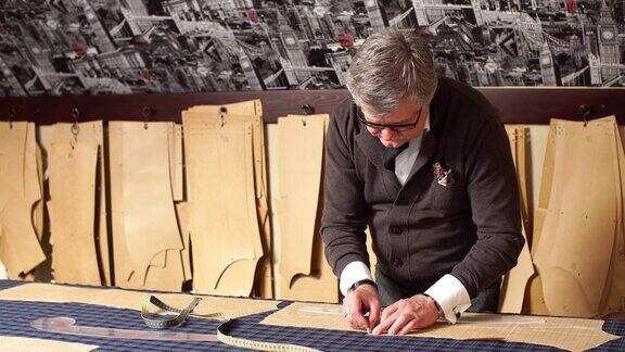 合格的熟练的有创意的设计师男性在展厅工作为纺织材料缝制样板