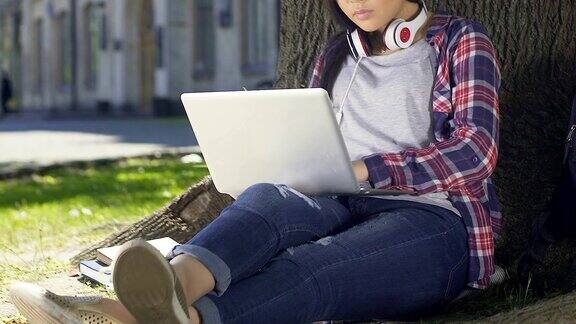 混血儿学生做她的文凭项目坐在露天笔记本电脑