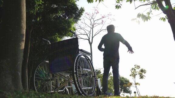 坐在轮椅上的亚洲老人在公园里伸展双臂