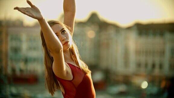 年轻优雅微笑的女芭蕾舞演员在夕阳下的屋顶上训练她的舞蹈