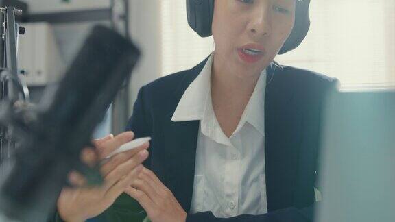 年轻的亚洲女商人录制和广播播客在她的笔记本电脑从工作室办公室