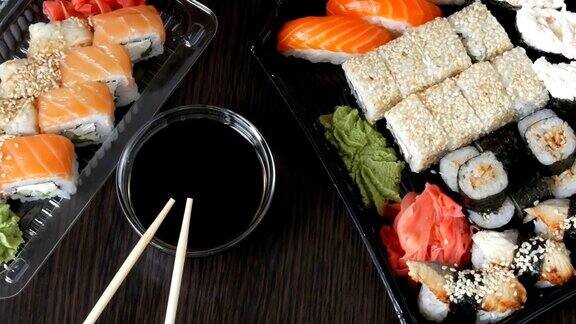 在时尚的黑色背景上配有各种寿司卷、寿司卷、手握寿司、粗看寿司酱油和竹筷就在旁边