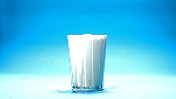 将牛奶倒入一个蓝色背景的玻璃杯中