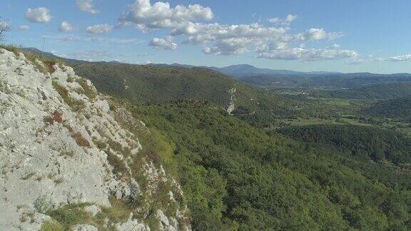 空中:飞过岩石峭壁飞向长满树林的草地和山丘