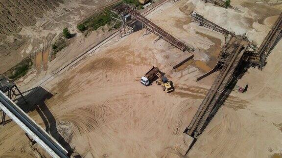 轮式装载机将沙子装进自卸卡车露天矿附近建筑用砂生产鸟瞰图