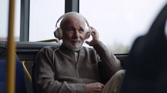 一位老人在公交车上戴着耳机听音乐