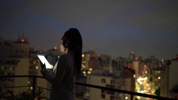 一位年轻的女商人在屋顶上思考和使用数字平板电脑