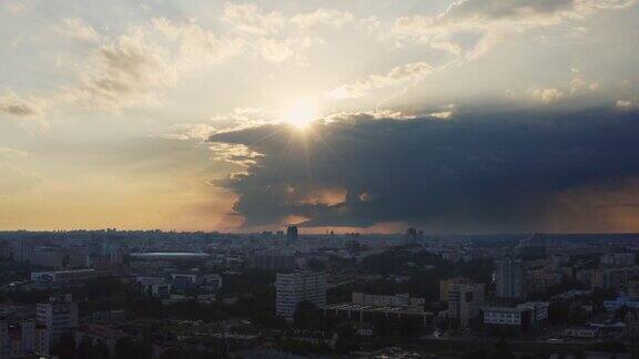 航空工业景观无人机在傍晚飞过城市上空夕阳下的乌云温暖的夏天过后城市开始下雨和雷雨阳光透过雷雨云照耀