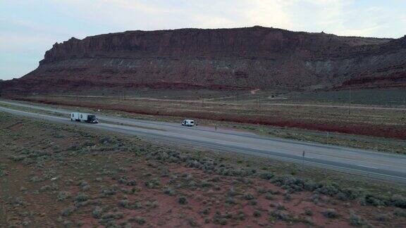 无人机观察半卡车在摩押附近的犹他州西南部红岩砂岩地区沙漠四车道高速公路上超速行驶