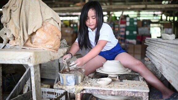 慢镜头亚洲华人波特小女孩用手和工具在波特轮上雕刻一个壶