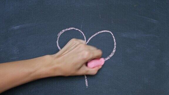 一个男人的手在黑板上用粉笔画了一个心形用红色粉笔在黑板上写字特写镜头
