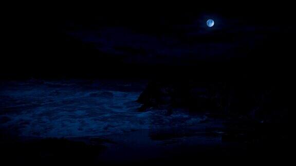 月光下海浪拍打着岩石沙滩