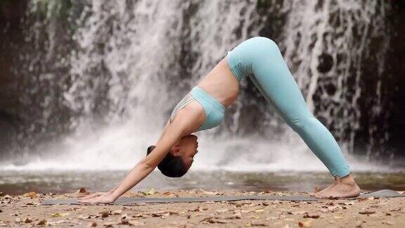 快乐女人瑜伽姿势平衡身体冥想在自然瀑布背景
