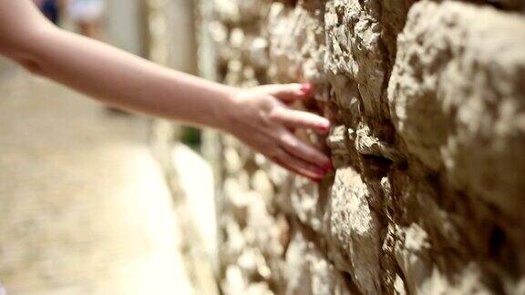 女孩触摸着古老的石墙