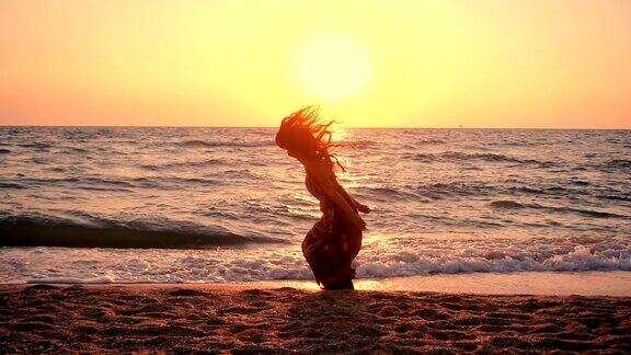 日出时美丽的女孩在海边跳跃