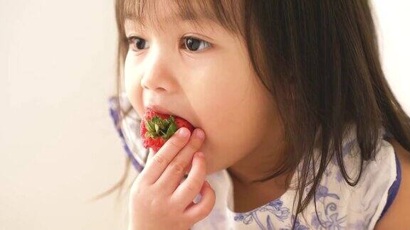 一个亚洲小女孩正在她的房间里吃草莓