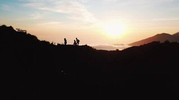 一群朋友的剪影沿着巴图尔活火山山顶在巴厘岛在日出4K