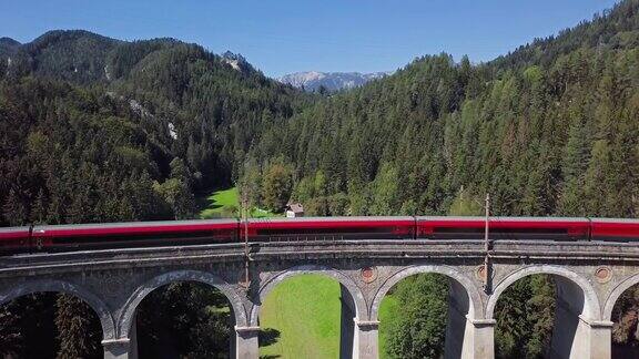 下奥地利历史悠久的塞默林铁路(塞默林铁路)上著名的卡尔特里恩高架桥上红色火车的鸟瞰图