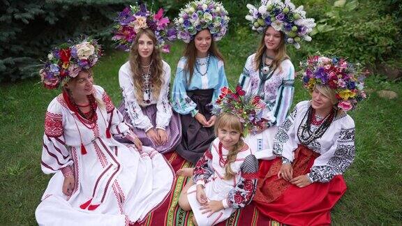 从高角度看美丽的乌克兰小女孩看着镜头坐在春夏季的草地上一群美丽的年轻女子穿着民族服装唱歌乌克兰和传统