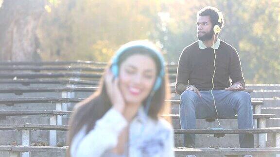 女人和男人在公园里戴着耳机听音乐