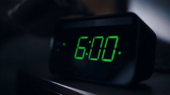 人醒来并关掉闹钟早起高效的人准备以新的冒险开始新的一天凌晨六点的时钟特写床头柜卧室公寓