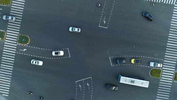 无人机旋转拍摄的城市十字路口汽车和公交车行驶在大道上在日落时