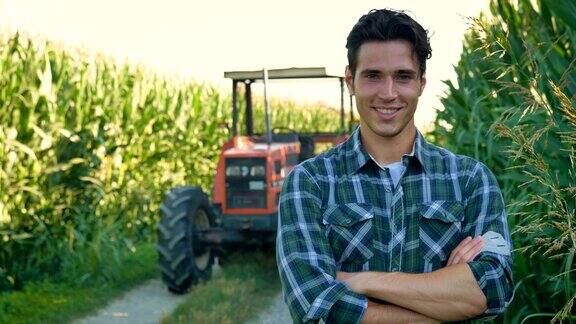 一个漂亮的年轻农民(学生)在田里和拖拉机一起工作成功的微笑快乐在一件衬衫玉米田