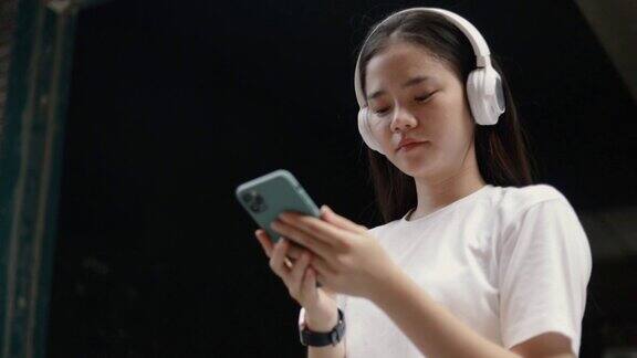迷人的亚洲女人戴着耳机听音乐