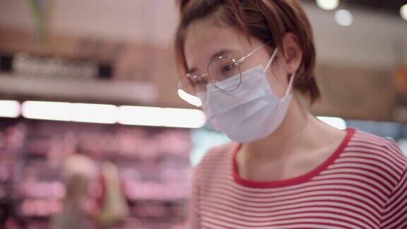 年轻女子戴着防护口罩在超市购物