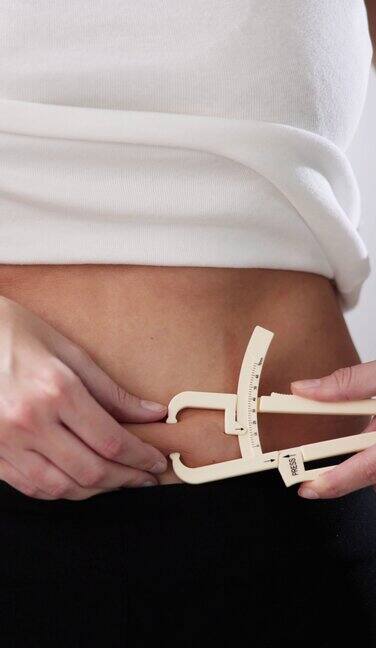 女性用手测量腹部脂肪