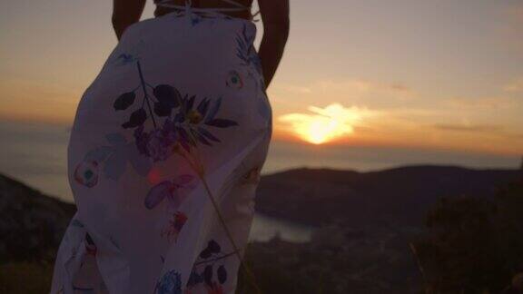 SLOMO不认识的女人在白色的裙子享受惊人的海景和美丽的日落
