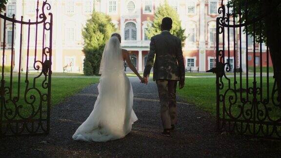 新郎和新娘正走向公园里的豪宅