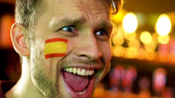 西班牙体育迷对自己最喜爱的球队获胜欣喜若狂脸上挂着国旗