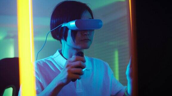 东亚职业玩家戴上虚拟现实耳机玩在线视频游戏与操纵杆控制器房间里的复古霓虹色很酷