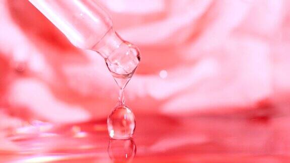 粉红色血清液油滴从滴管落在水中模糊的玫瑰花