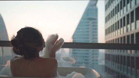 一名亚洲女子度假时在市中心豪华酒店浴室的浴缸里用肥皂泡洗澡