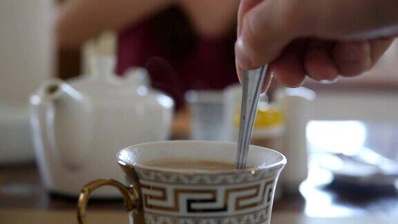 女性用手搅拌糖或牛奶在一杯热咖啡或茶中慢动作